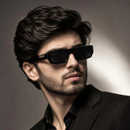 Man wearing black rectangular sunglasses with gold leopard logo detail – side profile lifestyle shot