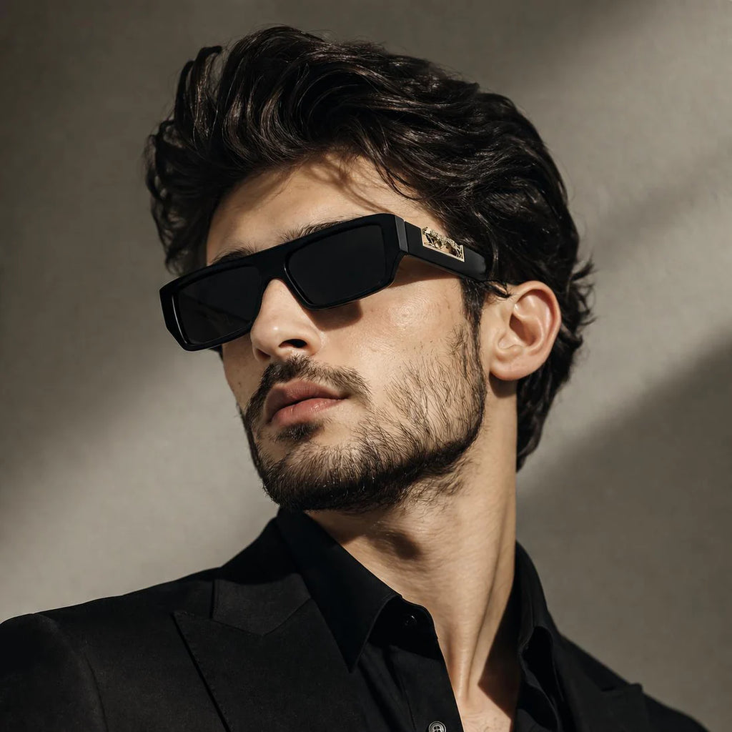 Man wearing black rectangular sunglasses with gold leopard logo – front lifestyle shot in natural light