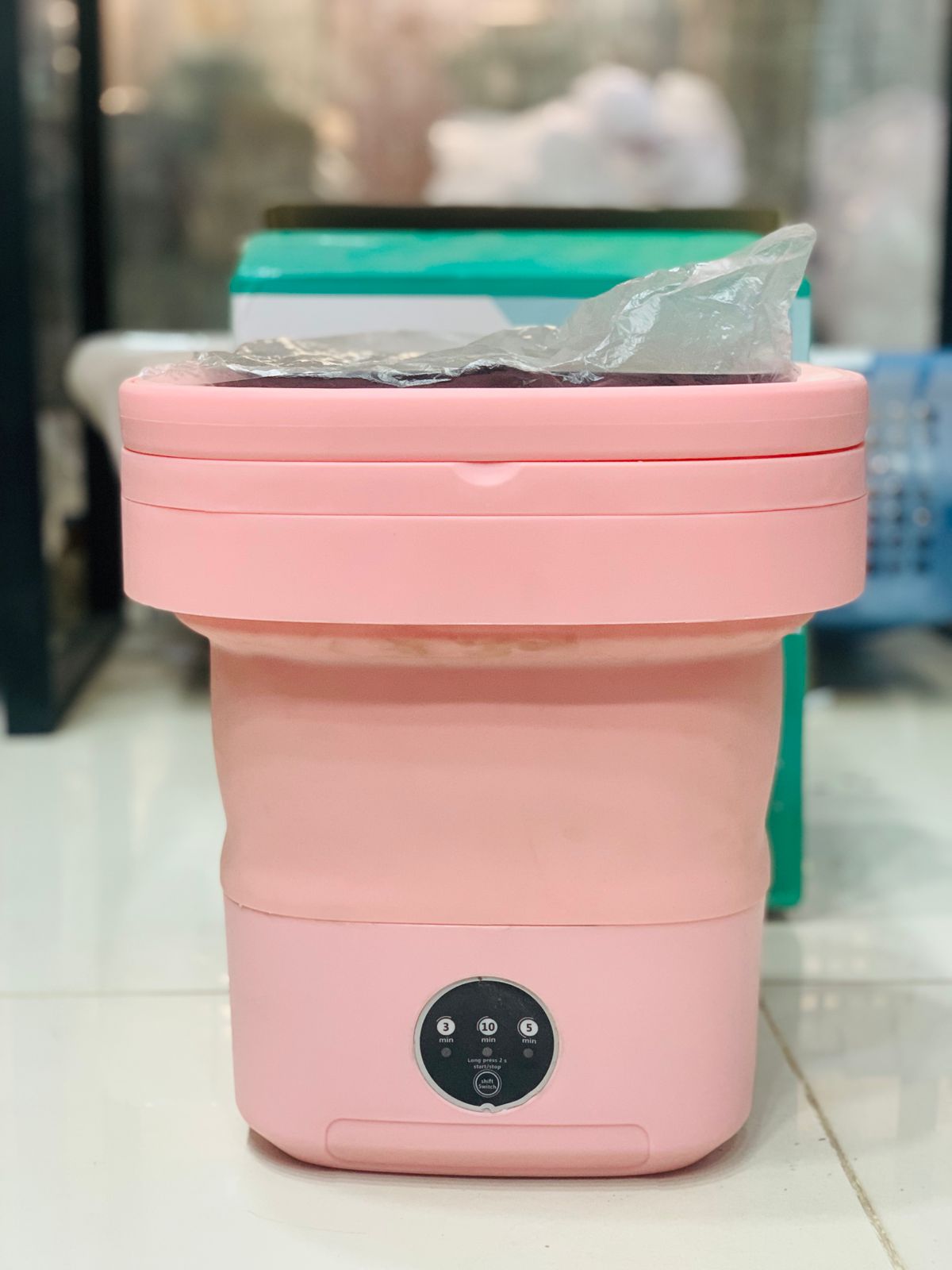 Folding washing machine unboxed showing all parts – tub, spin basket, drain hose and adapter