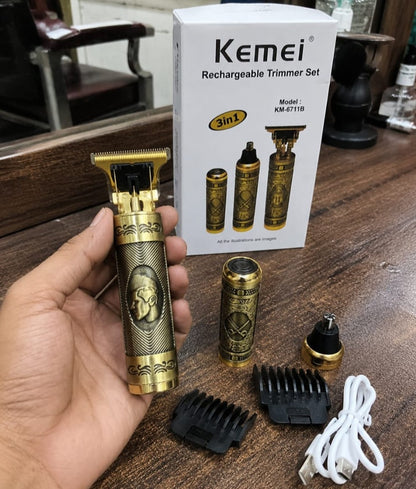 Kemei KM-6711B hair beard trimmer held in hand showing gold engraved antique design with box guide combs nose trimmer attachment and USB cable on wooden barbershop table