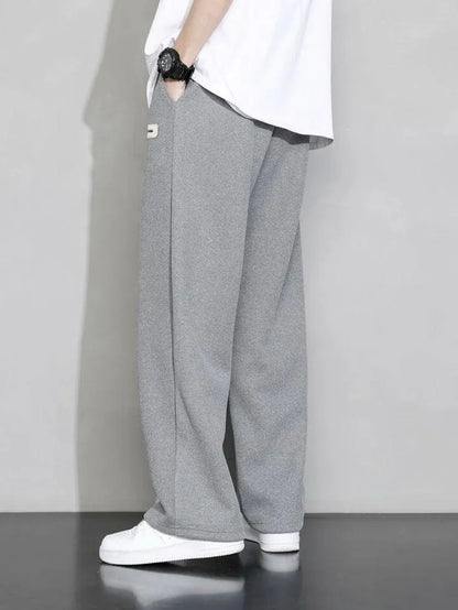 Man wearing grey premium micro plain trouser with white t-shirt and white sneakers – side view lifestyle shot on grey background