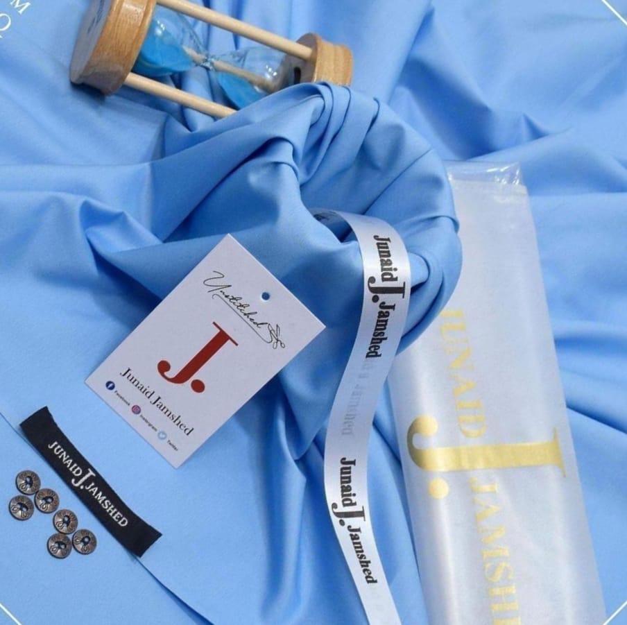 Junaid Jamshed Sky Blue Wash N Wear unstitched fabric close up showing soft texture with brand tag and branded ribbon