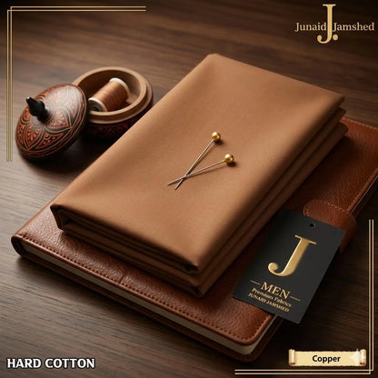 Junaid Jamshed Hard Cotton unstitched fabric in Copper color folded on leather journal with J. Men premium fabrics tag close up