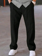 Man wearing black dri-fit plain drawstring trouser with grey t-shirt and white sneakers – close up front view on concrete background