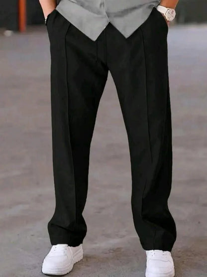 Man wearing black dri-fit plain drawstring trouser with grey t-shirt and white sneakers – close up front view on concrete background