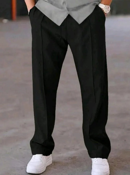 Man wearing black dri-fit plain drawstring trouser with grey t-shirt and white sneakers – close up front view on concrete background