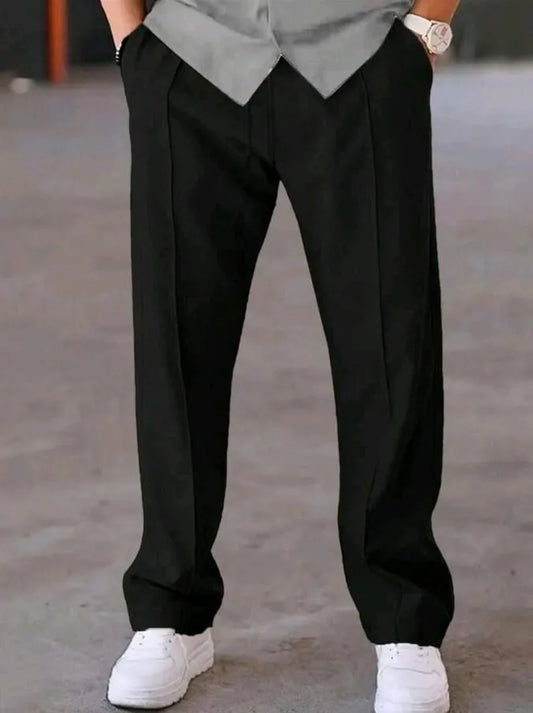 Man wearing black dri-fit plain drawstring trouser with grey t-shirt and white sneakers – close up front view on concrete background