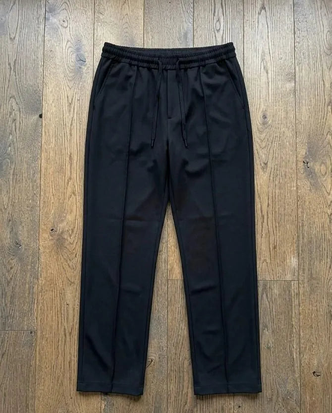 Black dri-fit plain drawstring trouser laid flat on wooden floor – full length top view product shot