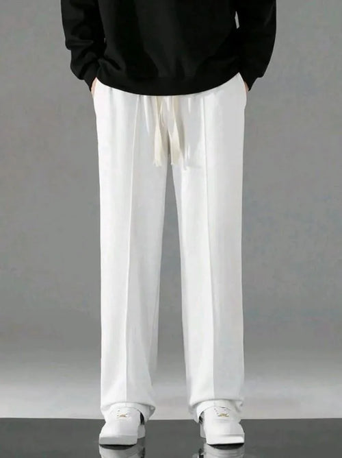 Man wearing white dri-fit drawstring trousers with black hoodie and white sneakers – front model shot on grey background