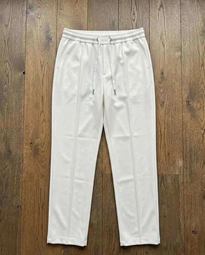 White dri-fit drawstring trousers laid flat on wooden floor – full length product shot