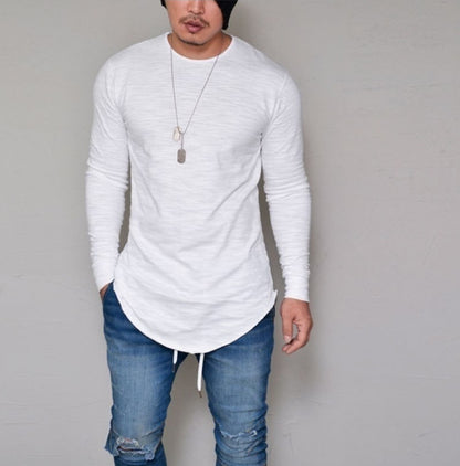 Man wearing white slim fit long sleeve round neck curved hem t-shirt with ripped jeans – front lifestyle model shot on grey background