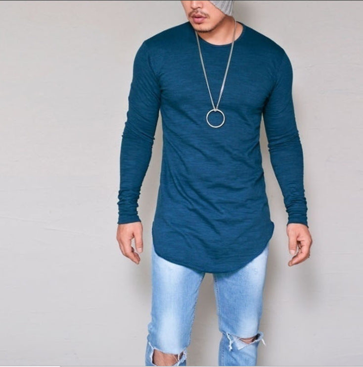 Man wearing teal slim fit long sleeve round neck curved hem t-shirt with ripped jeans – front lifestyle model shot on grey background