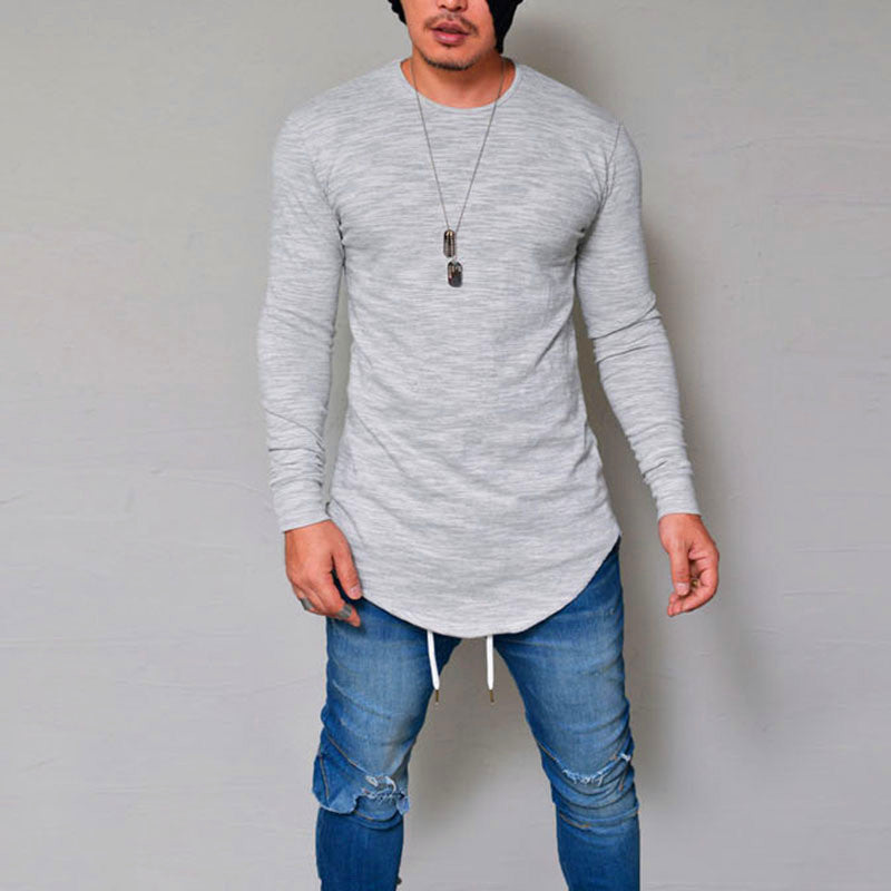 Man wearing grey slim fit long sleeve round neck curved hem t-shirt with ripped jeans – front lifestyle model shot on grey background
