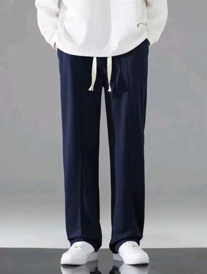 Man wearing navy blue dri-fit drawstring trousers with white hoodie and white sneakers – front model shot on grey background