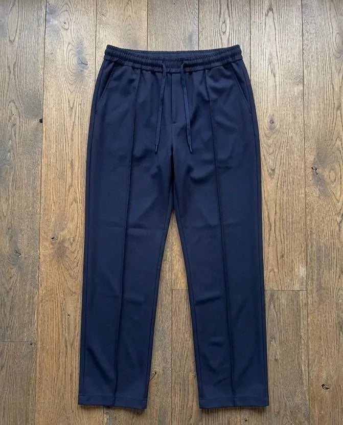 Navy blue dri-fit drawstring trousers laid flat on wooden floor – full length product shot