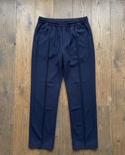 Navy blue dri-fit drawstring trousers laid flat on wooden floor – full length product shot